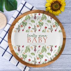 a wooden platter with the words, locally grown baby printed on it next to a sunflower