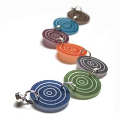 four different colored circles are attached to a keychain on a white surface,