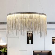 a chandelier hanging from the ceiling in a living room with white walls and flooring