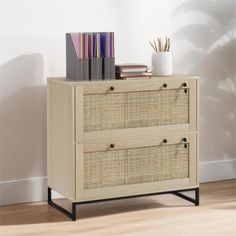 a wooden dresser with two drawers and books on top