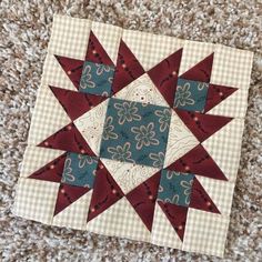 a red and blue quilted star sitting on top of a floor next to a rug