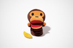 a stuffed monkey with its mouth open next to a peeled banana on a white background