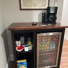 a mini fridge is next to a counter with drinks and snacks on it in a kitchen