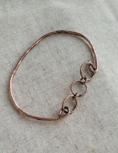 "Hand forged 12-gauge copper wire shaped and hammered into a beautiful bangle bracelet with three copper links adding interest and detail.    I've oxidized and polished to bring out the natural beauty of the copper. I can add a clear coating to prevent further oxidation if you would like. Care Instructions: - Remove your jewelry before showering, sleeping, swimming or sweating. - Most pieces, unless otherwise specified, can be cleaned with a mild dish soap and soft toothbrush  if really necessary. Do NOT soak your jewelry or use any chemicals. - Clean your jewelry before and after each use with a soft dry polishing cloth.  >Please keep in mind when ordering that color settings on your  screen and lighting in product photography vary so the product might  differ a tad from what you see on s Hammered Bronze Metal Bracelets, Bronze Hammered Metal Bracelets, Carrot Jewelry, Bracelet Photography, Hammered Wire Jewelry, Copper Wire Bracelet, Hammered Copper Earrings, Matching Couple Bracelets, Hammered Bracelet