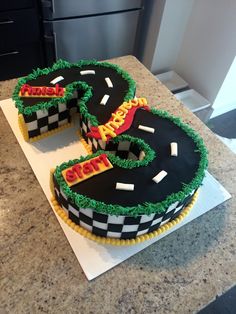 two birthday cakes shaped like the number five on a counter top with cars driving around them