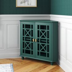 a green cabinet sitting in the corner of a room next to a painting on the wall