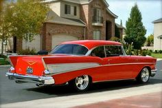 an old red car parked in front of a house