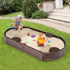 a baby playing in a sandbox on the grass