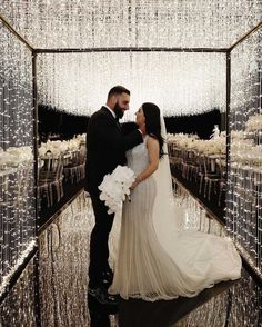 a bride and groom standing in front of a large display of crystal chandeliers