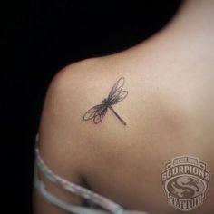 the back of a woman's shoulder with a dragonfly tattoo on it