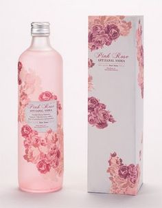 a bottle of pink rose water next to a box on a white background with flowers