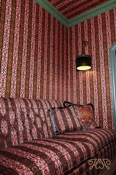 a bed sitting in the corner of a room next to a lamp on a wall