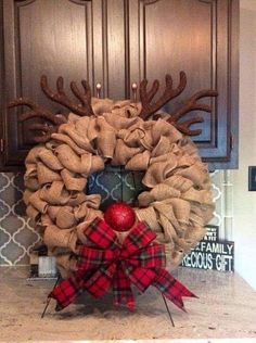 a christmas wreath with antlers and an apple on the kitchen counter next to cabinets