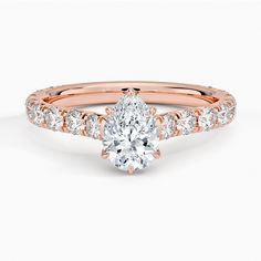 a rose gold engagement ring with a pear shaped diamond in the center and side stones