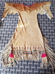 a piece of cloth with fringes laying on top of a blue carpeted floor