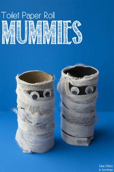 two toilet paper roll mummies sitting on top of each other in front of a blue background