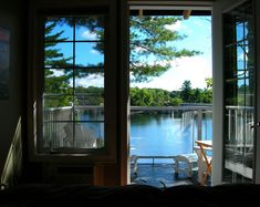 an open door leading to a bedroom with a view of the water and trees outside