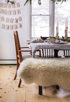 a dining room table and bench with candles on the window sill in the background