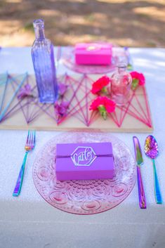 the table is set with pink and purple decorations