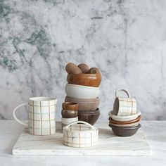 a stack of bowls and cups sitting on top of a marble slabd countertop