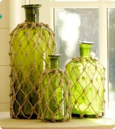 two green vases sitting on top of a window sill next to a cord