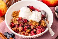 a bowl filled with fruit and ice cream on top of a pink cloth next to cinnamon sticks