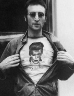 black and white photograph of a man holding up a shirt with an image of elvis presley on it