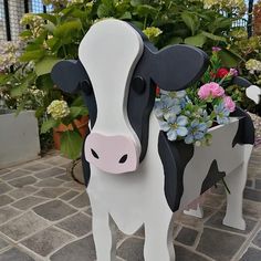 a black and white cow planter with flowers in it