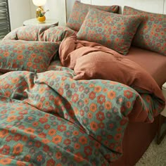 an orange and blue comforter on top of a bed in a bedroom next to a night stand