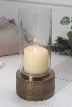 a lit candle in a glass container on a table