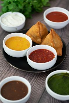 some dipping sauces are on a black plate