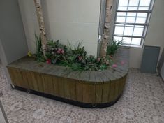 a wooden bench with flowers on it in front of a mirror and tile flooring