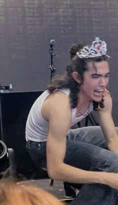 a man with a crown on his head sitting in front of a microphone