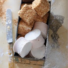 a box filled with marshmallows next to a knife and some powdered sugar