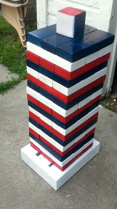 a red, white and blue building made out of legos on the sidewalk next to a house