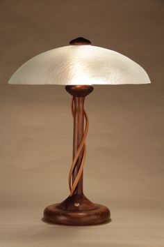 a wooden table lamp with a white glass shade on it's base and cord wrapped around the top