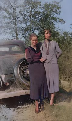 two women standing next to an old car