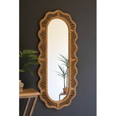 an oval mirror hanging on the wall next to a potted plant and wooden table