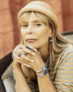 a woman sitting down with her hand on her chin and looking off to the side