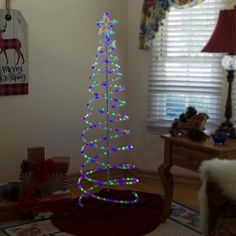 a lighted christmas tree sitting in the corner of a living room next to a window