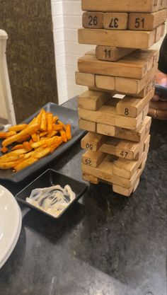 a stack of wooden blocks sitting on top of a table next to some fries and dip