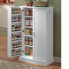 an open cabinet with food in it on the floor next to a potted plant