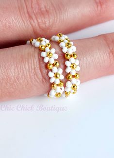 a woman's hand wearing a gold and white beaded ring