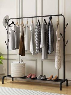 an iron rack with shoes and clothes hanging on the wall next to a potted plant