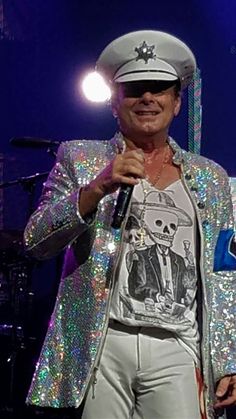 a man in a sequin jacket singing into a microphone