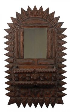 an ornate wooden mirror with spikes on the sides and a shelf below it that has a mirror above it