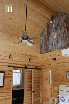 a bedroom with wooden walls and ceiling fan in the middle of it's room