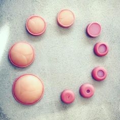 pink buttons arranged in the shape of a heart on a gray surface with white background