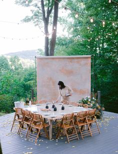 a woman standing in front of a table with chairs