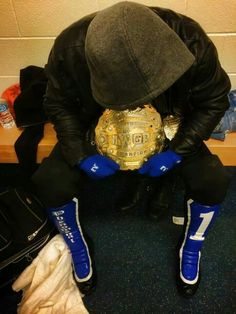 a man kneeling down holding a wrestling belt